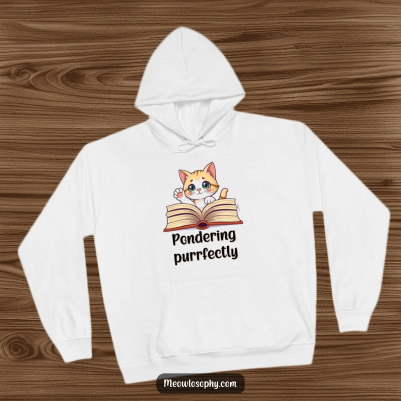 Funny hoodie with a curious cat peeking through a large book, one paw thoughtfully raised, for literary comfort.