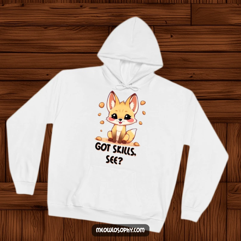 Funny hoodie featuring a mischievous fennec fox juggling pebbles, offering warmth and playful charm for cozy days.